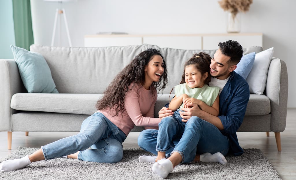 A family relaxing together on the floor of a bright, comfortable living room